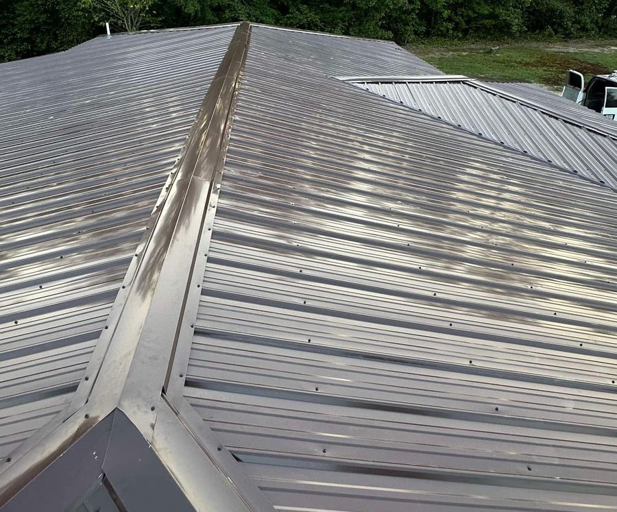 A close-up of a metal roof with trees in the background