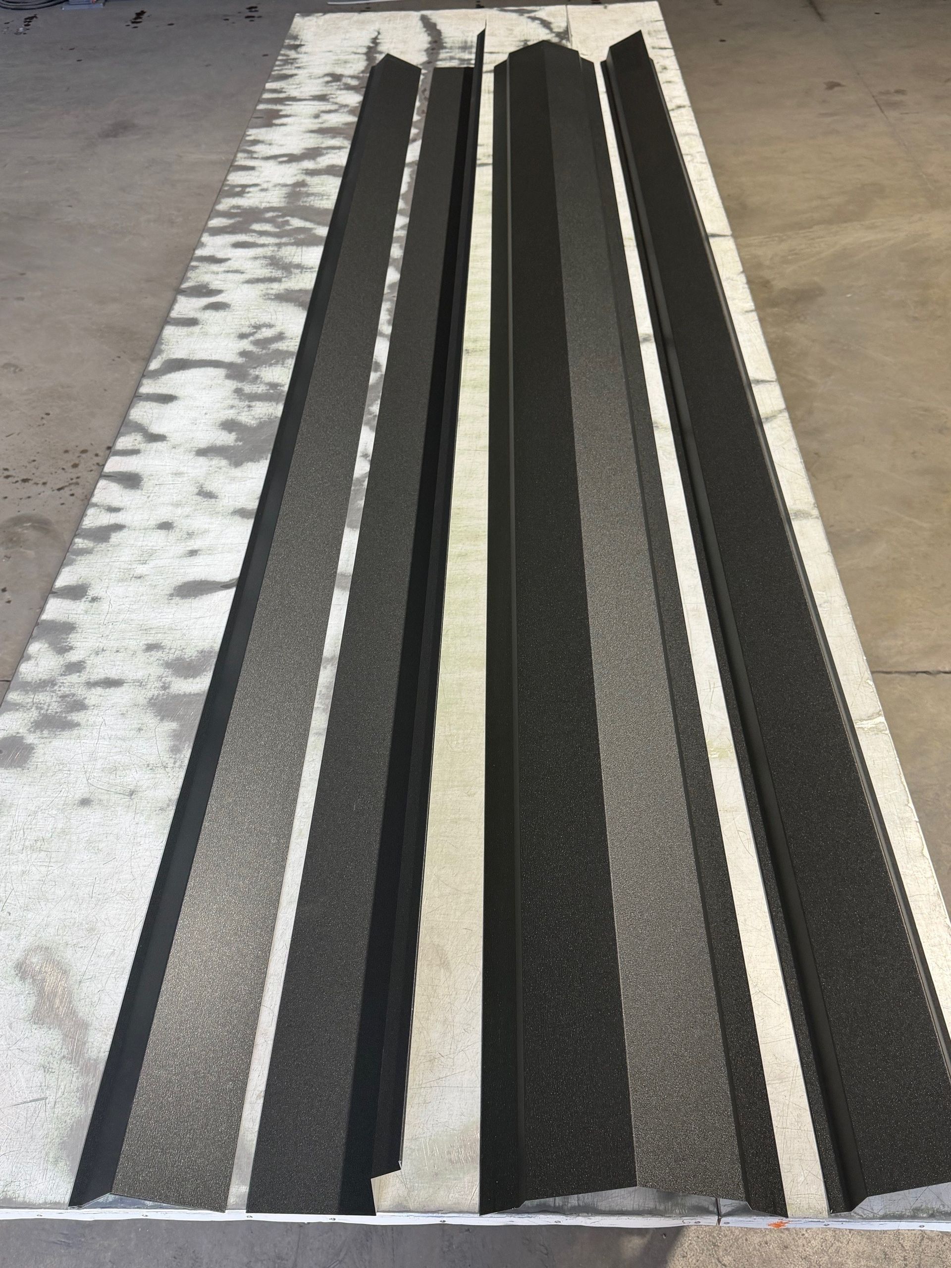 A rectangular panel featuring parallel, dark, textured raised ribs separated by light-colored flat strips.