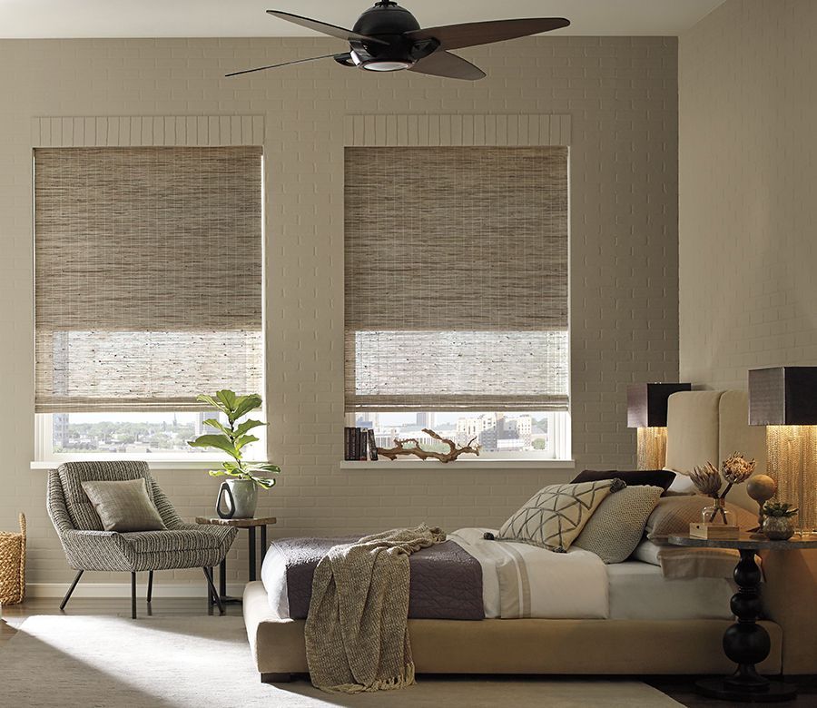 A bedroom with a bed a chair and a ceiling fan
