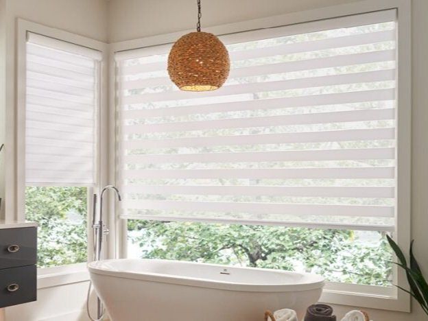 A bathroom with a tub and a window with blinds.
