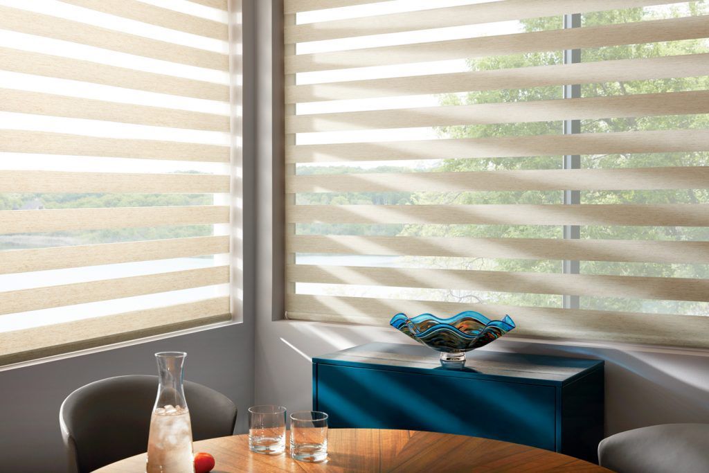 A dining room with a table and chairs and a window with striped blinds.