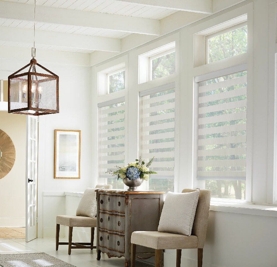 A living room with a dresser , chairs , and a clock on the wall.