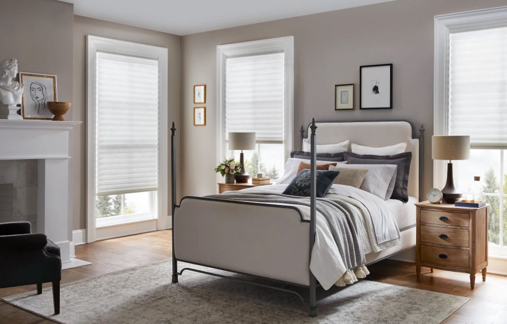 A bedroom with a four poster bed , nightstands , lamps and a fireplace.