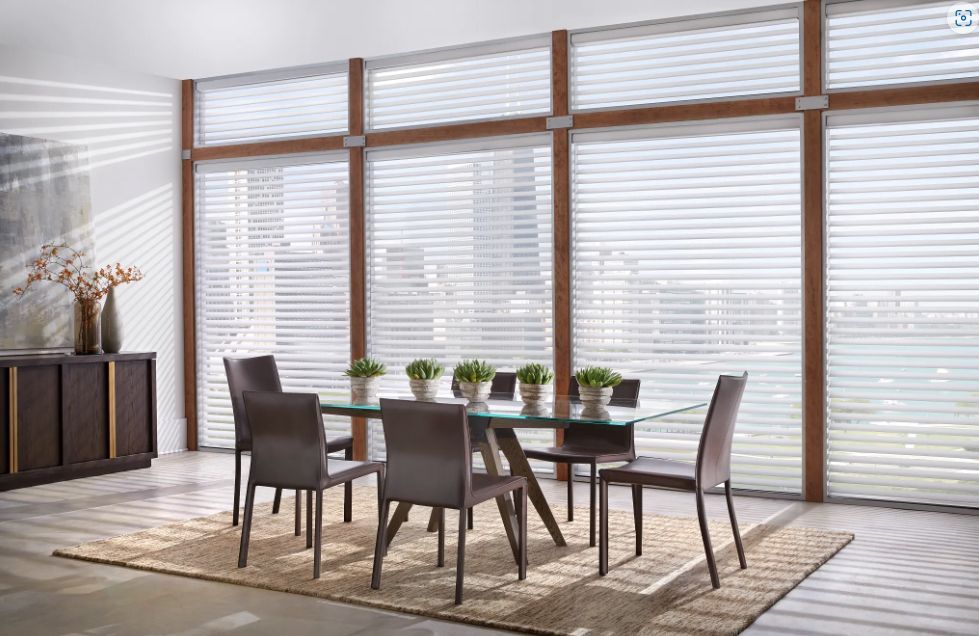 A dining room with a table and chairs in front of a large window.