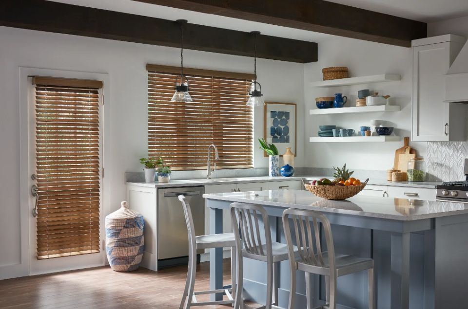 A kitchen with a large island and wooden blinds on the windows.