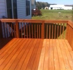 A wooden deck with a railing and a house in the background.