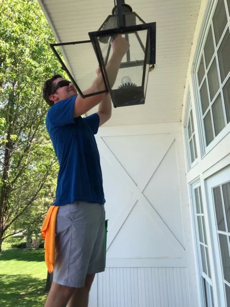 A man in a blue shirt is hanging a lantern from the ceiling