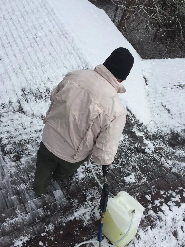 A man is standing on a snowy staircase with a bucket of water.