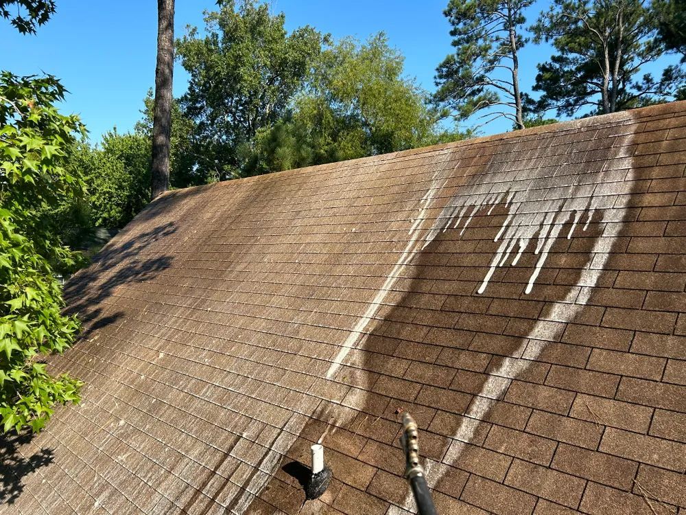 A roof is being cleaned with a pressure washer.