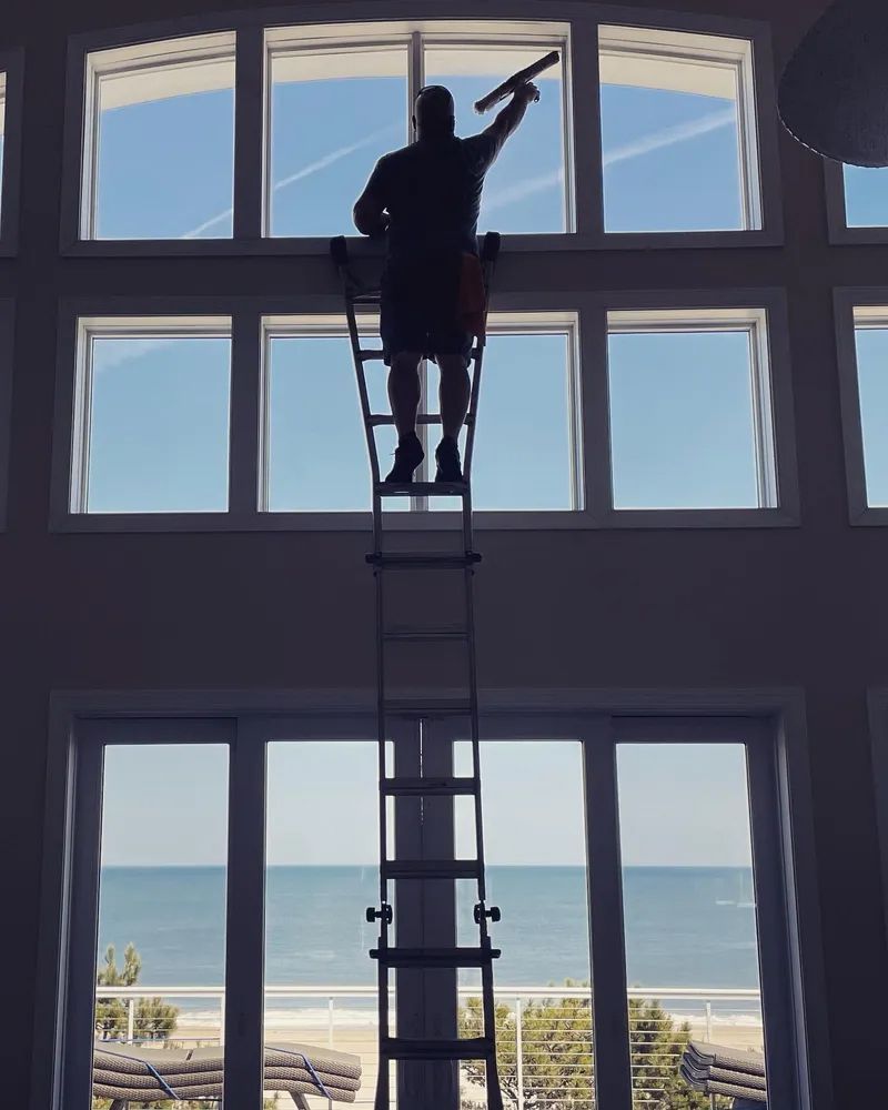 A man is standing on a ladder cleaning a window