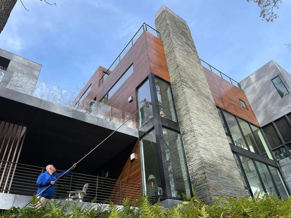 A man is cleaning the windows of a large house.