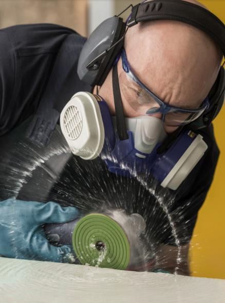 Person sanding a light-colored countertop inside a workshop