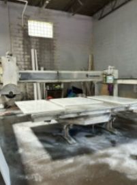 Large stone cutting machine in a workshop setting, cutting a slab.