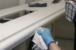 Person in blue gloves wiping a white countertop; tools in background.
