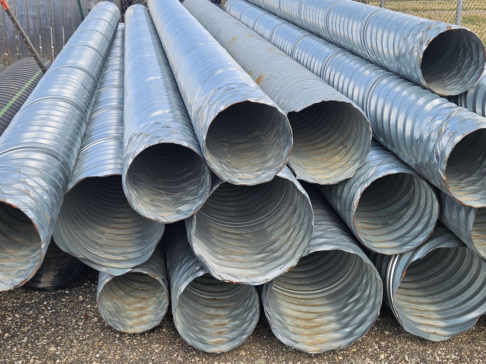Stacked corrugated metal drainage pipes piled outdoors