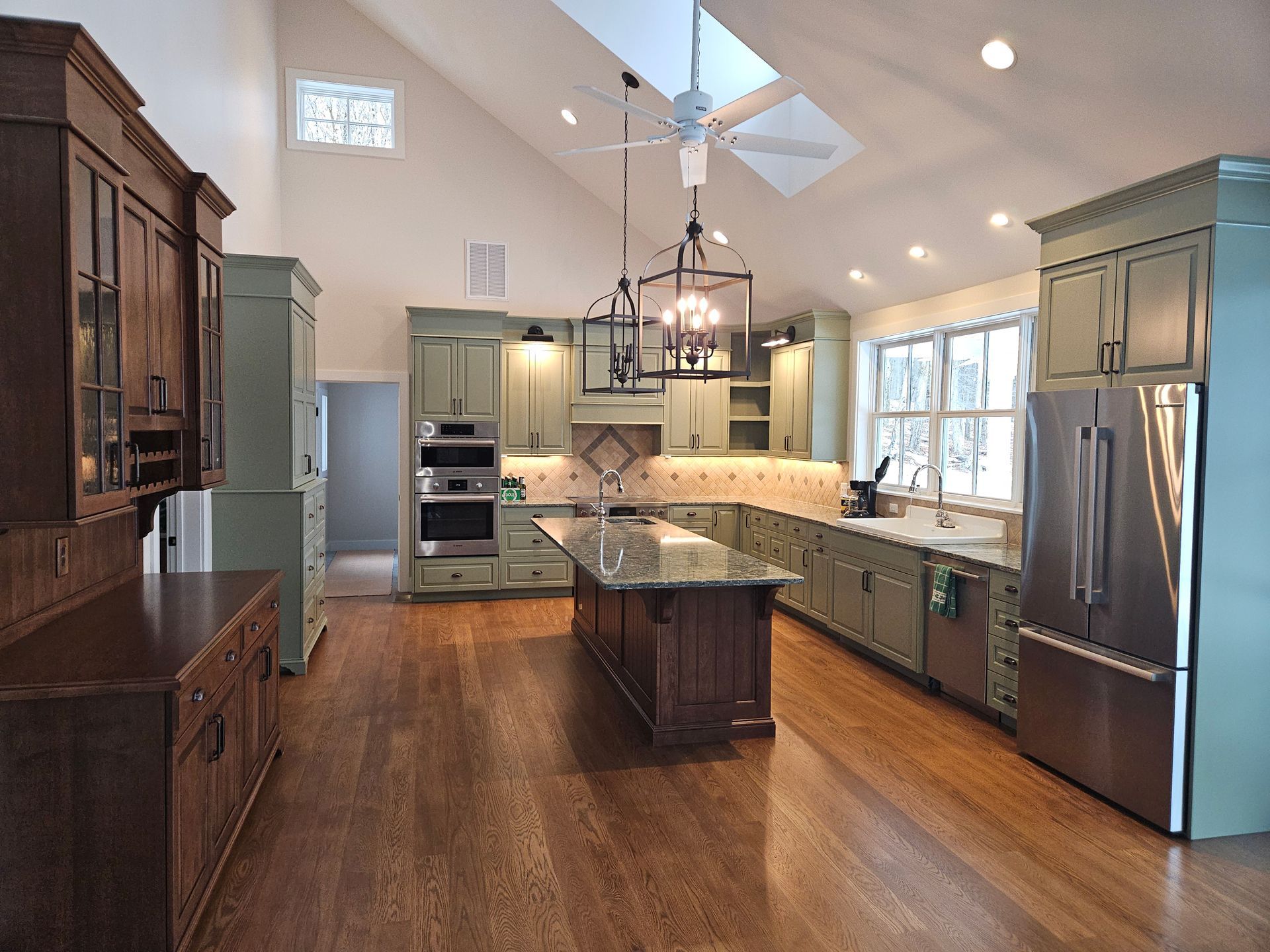 A large kitchen with green cabinets and stainless steel appliances