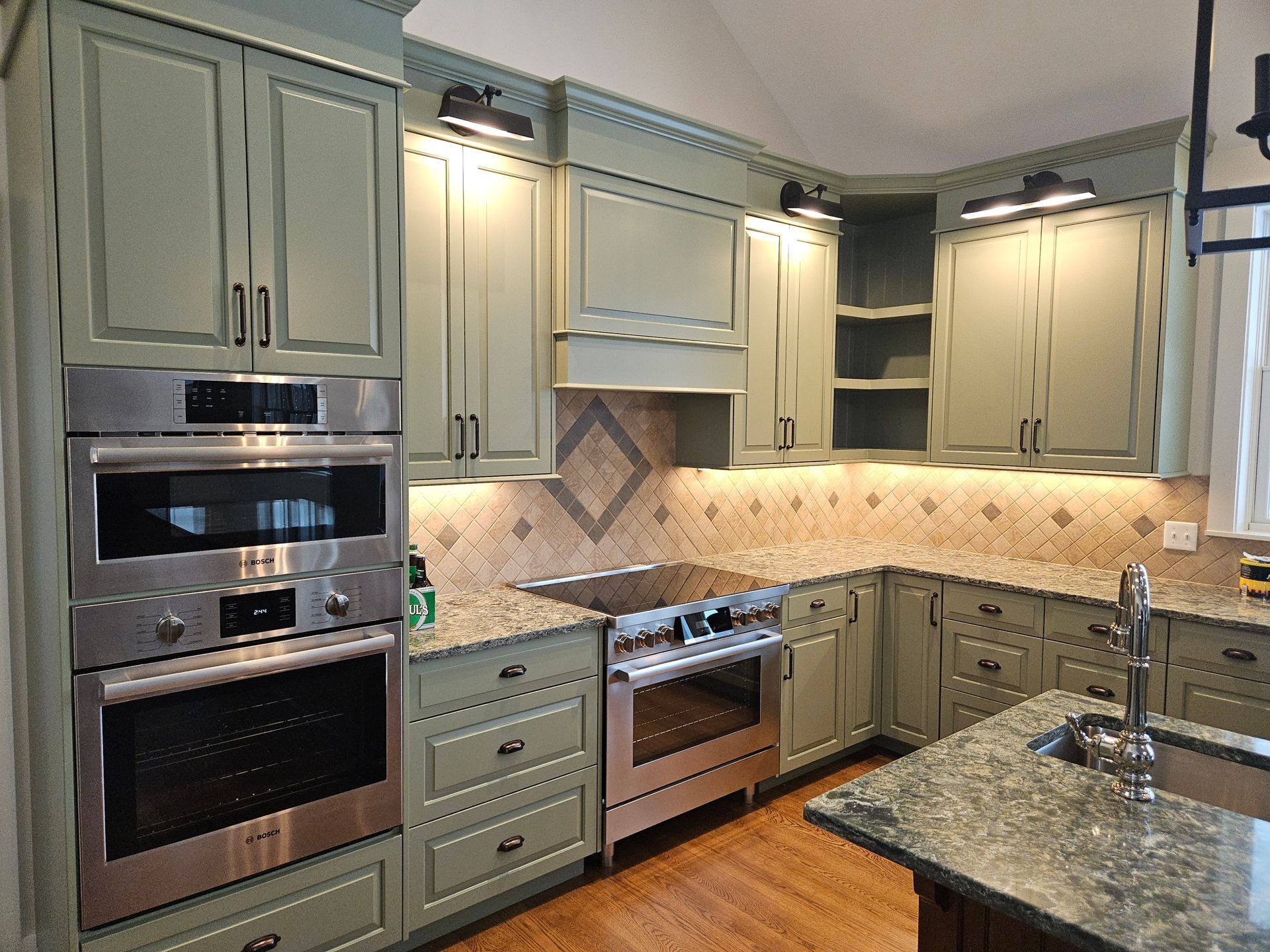 A kitchen with green cabinets and stainless steel appliances