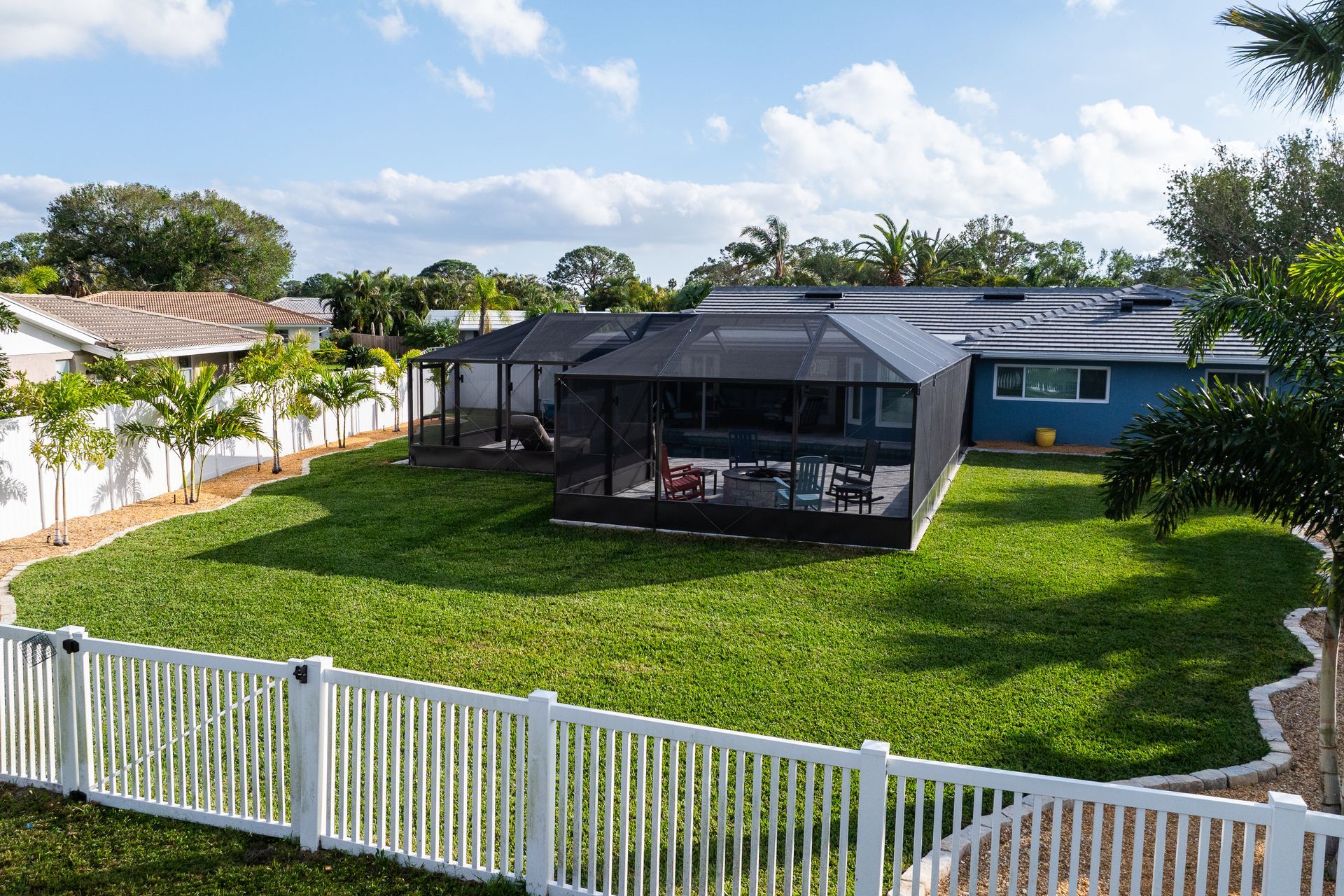 A large backyard with a white fence and a screened in porch.