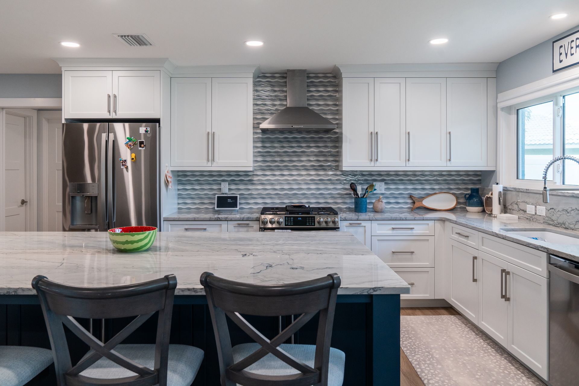 A kitchen with white cabinets, stainless steel appliances, and a large island.