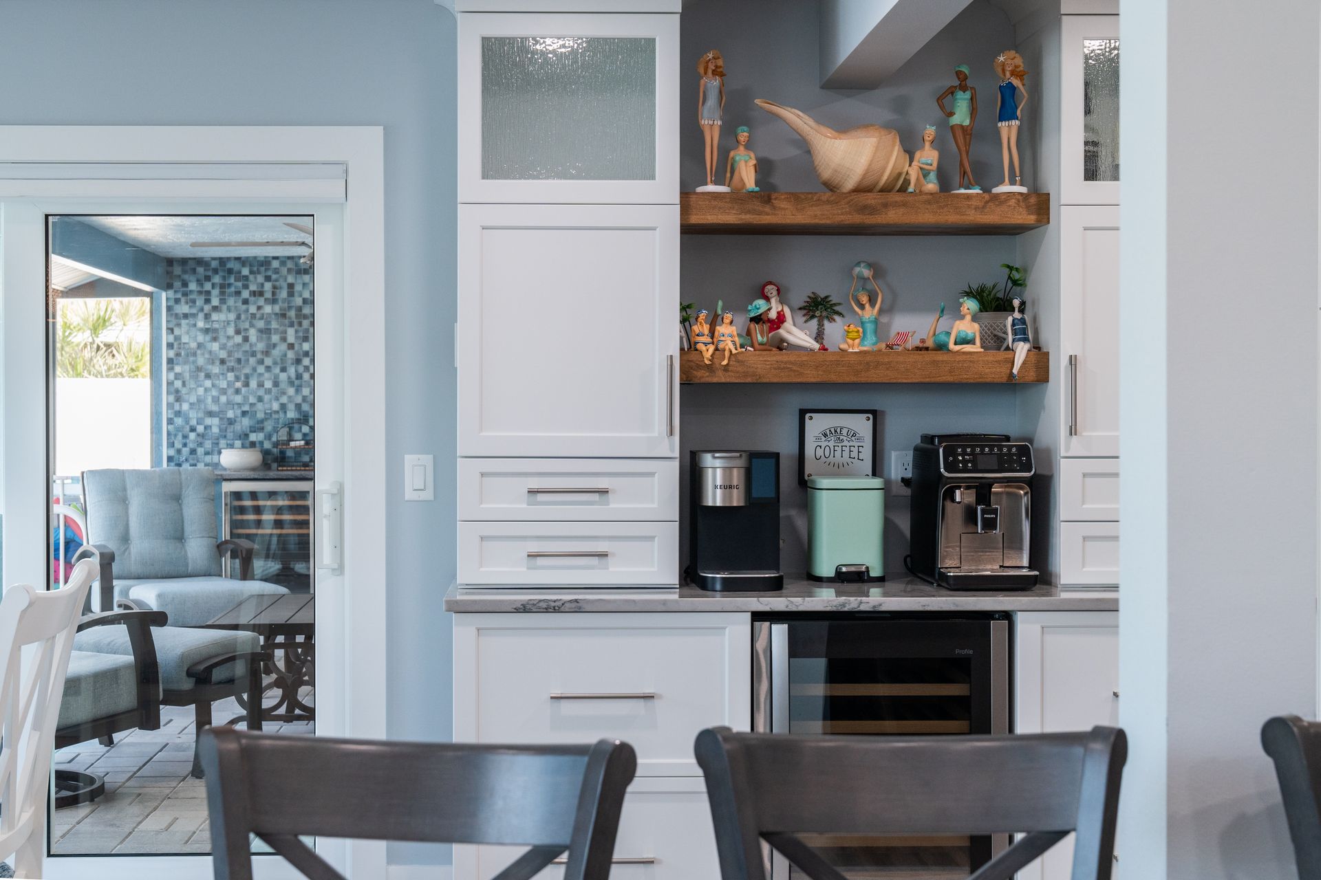 A kitchen with white cabinets, a refrigerator, a microwave, and a wine cooler.