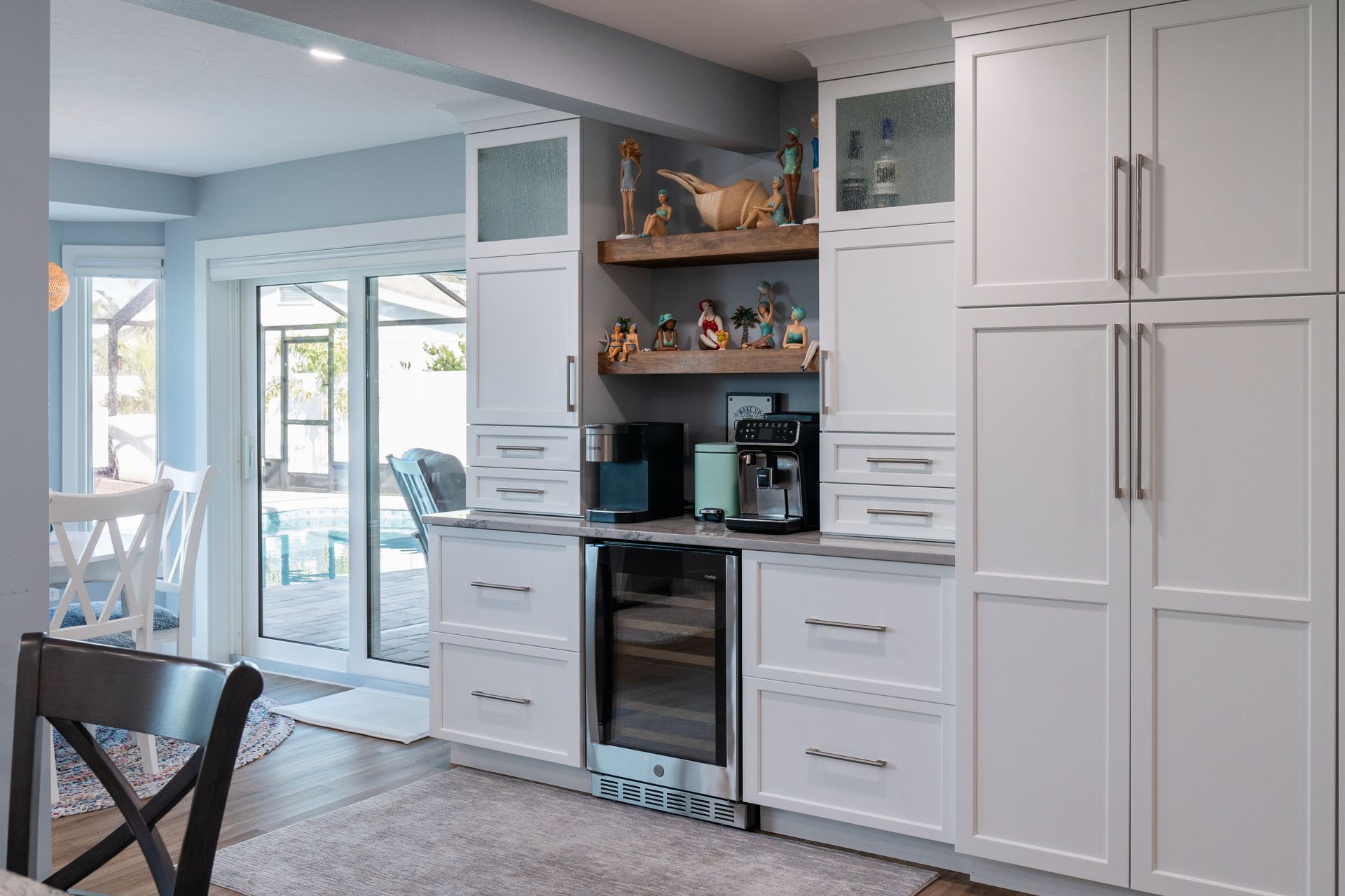 A kitchen with white cabinets , a refrigerator and a wine cooler.