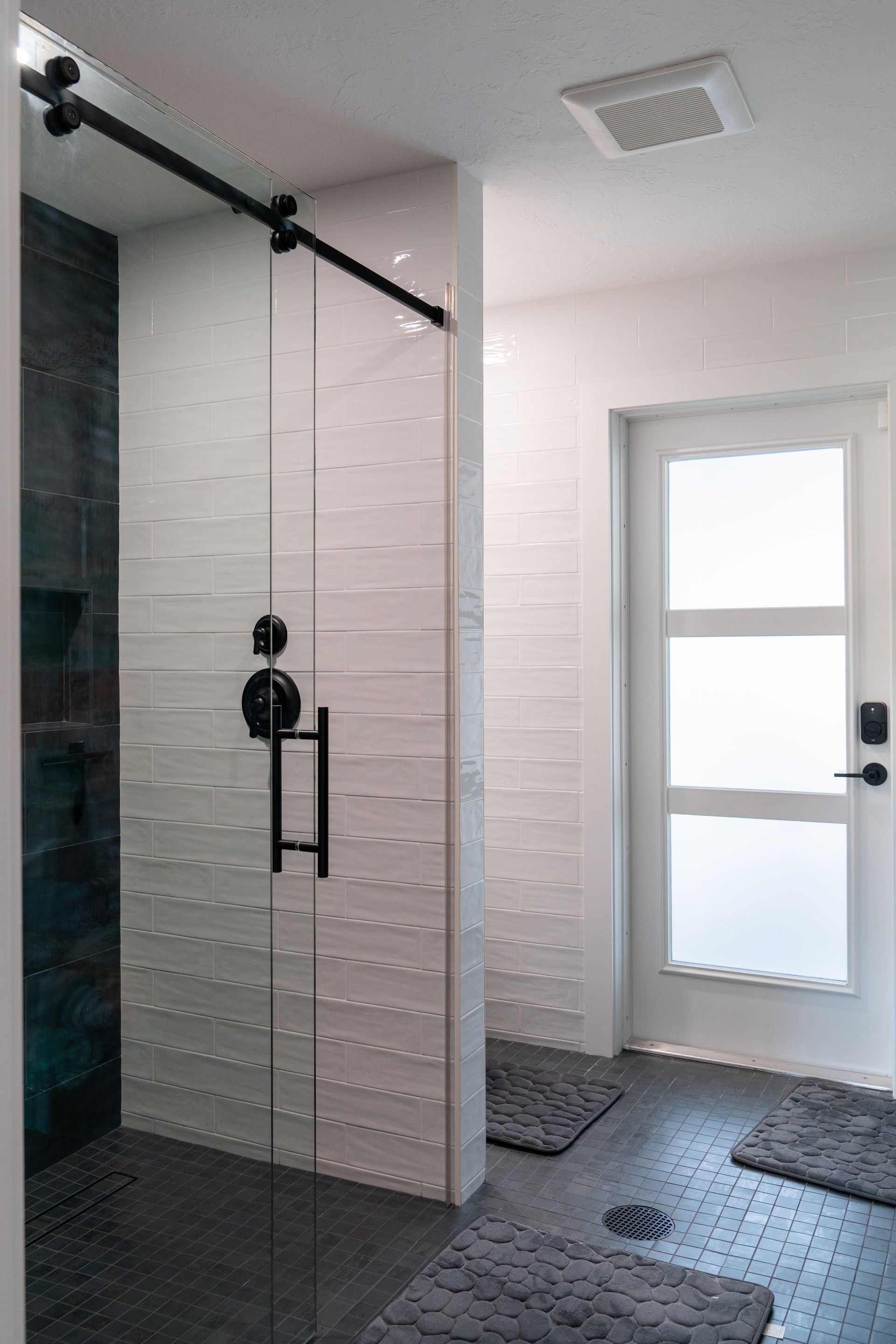 A bathroom with a walk in shower and a sliding glass door.