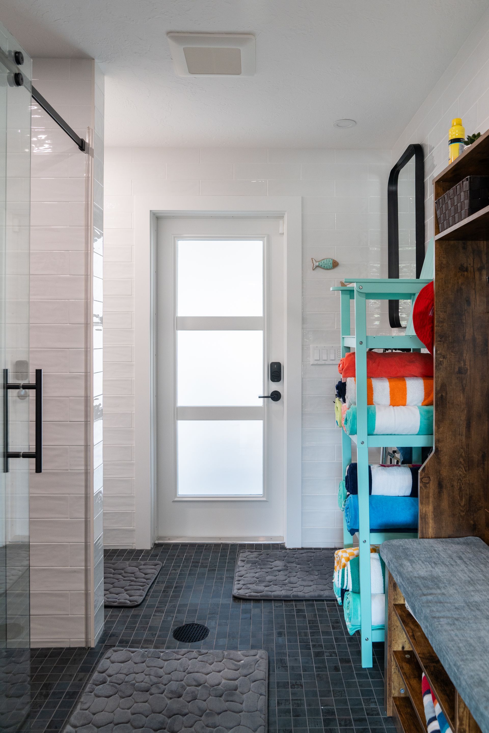 A bathroom with a white door and a walk in shower.