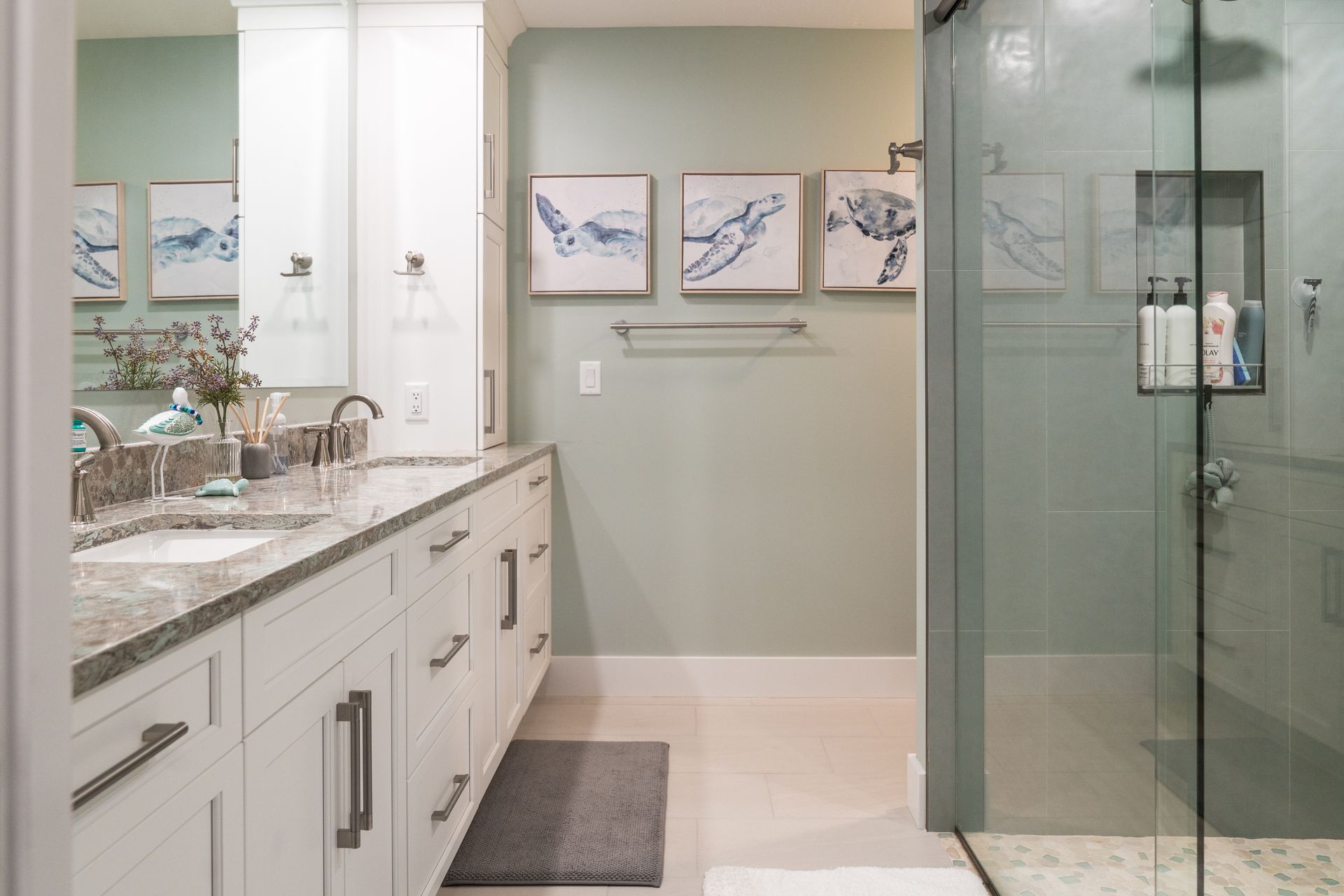 A bathroom with two sinks and a walk in shower.