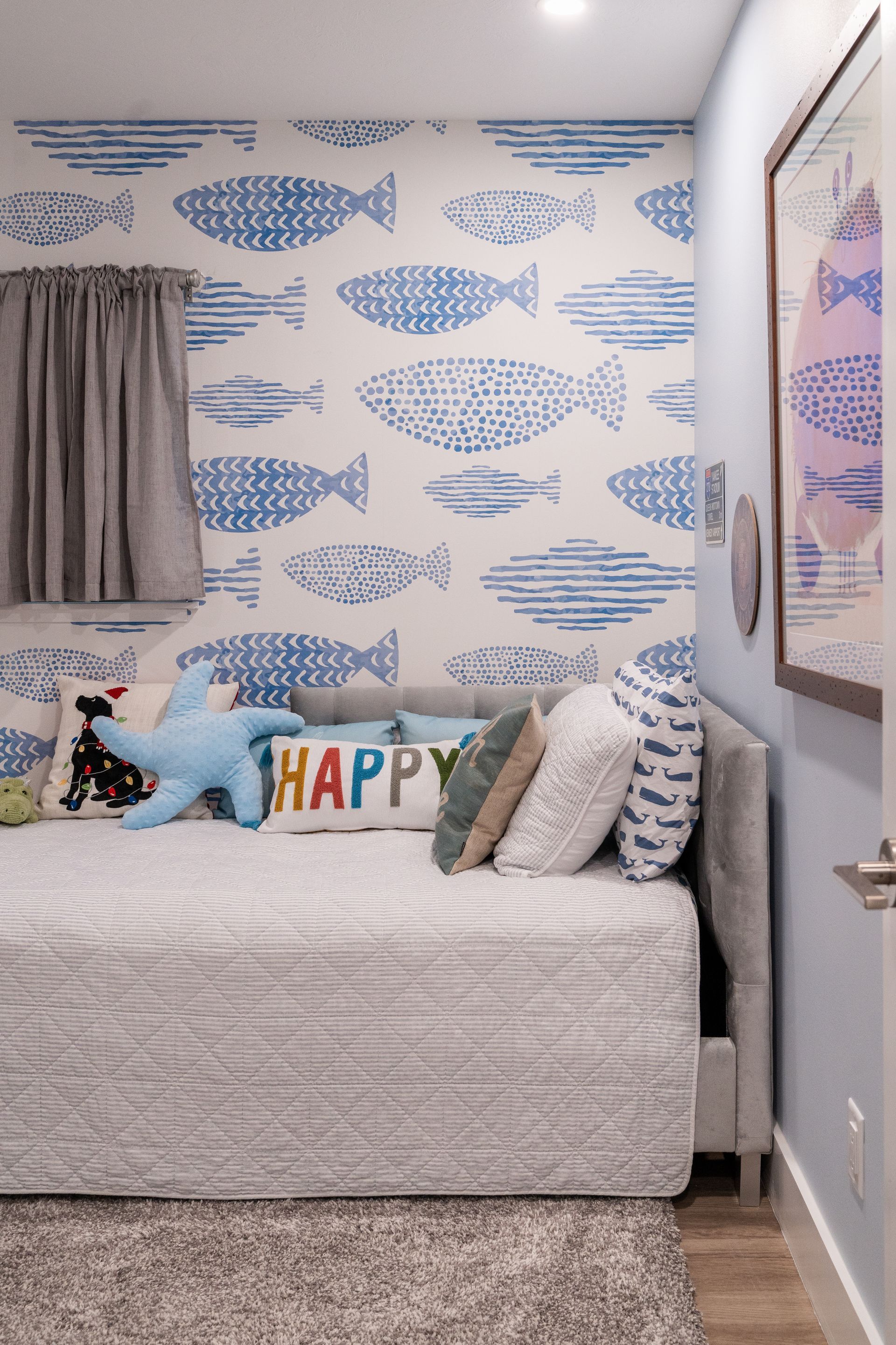 A bedroom with a bed, couch, pillows, and a sign that says happy.