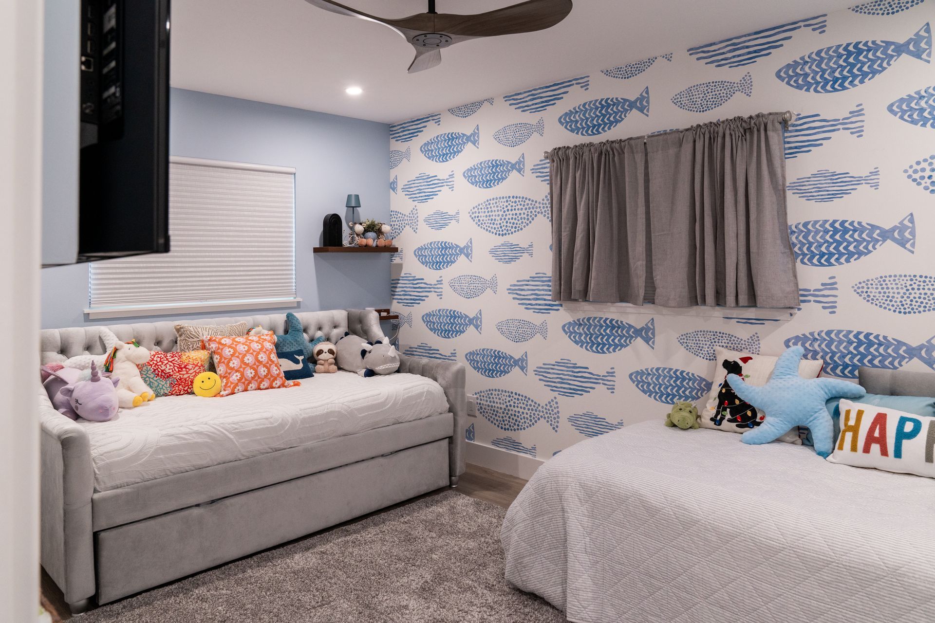 A bedroom with two beds, a day bed ,and a ceiling fan.