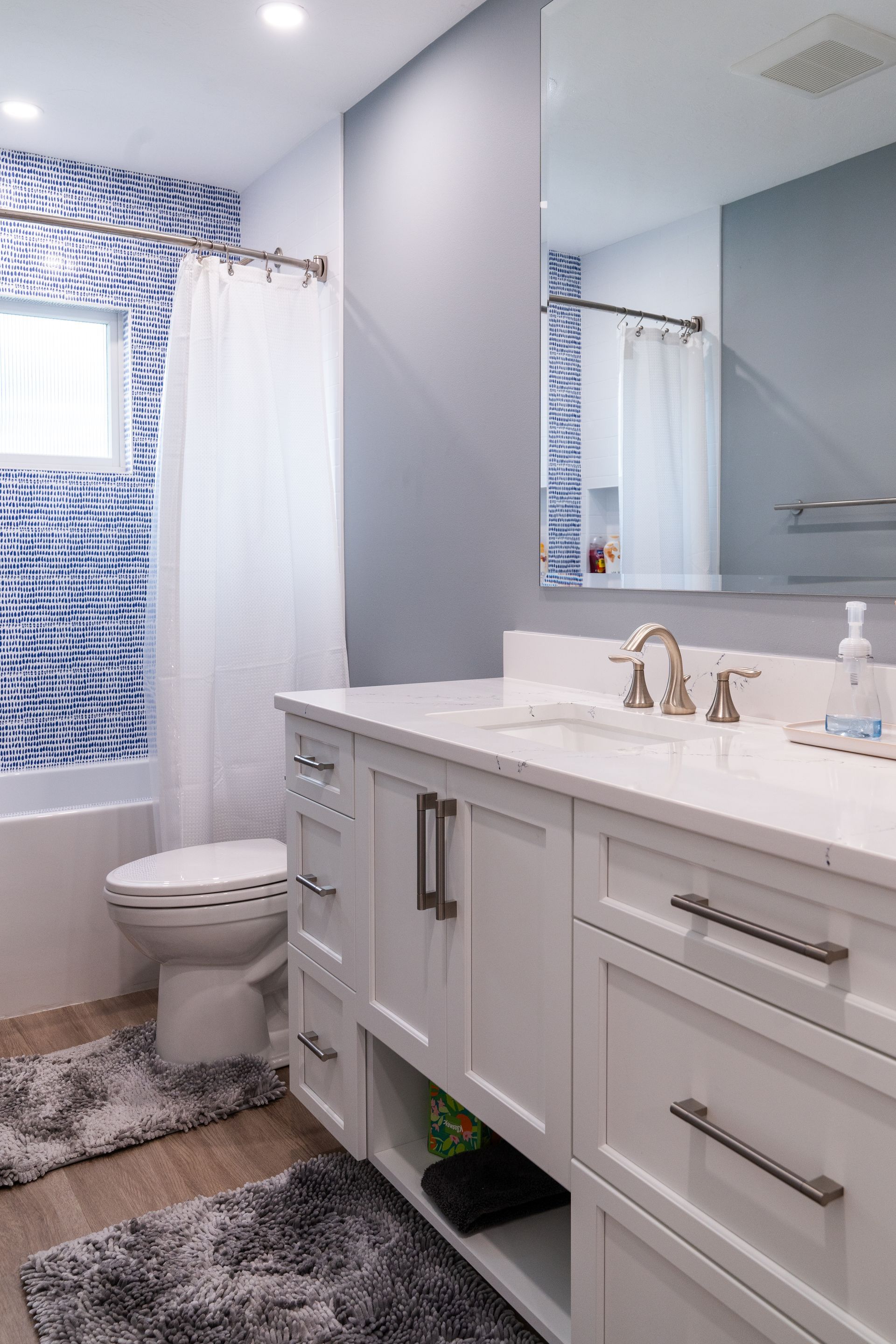 A bathroom with a toilet, sink, and mirror.