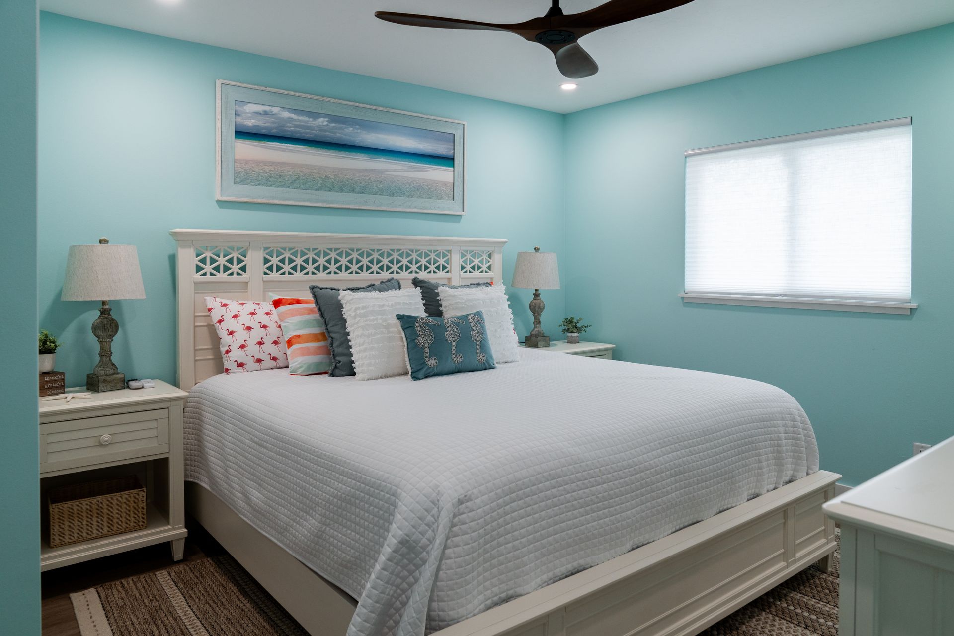 A bedroom with a king-size bed, nightstands, lamps, and a ceiling fan.