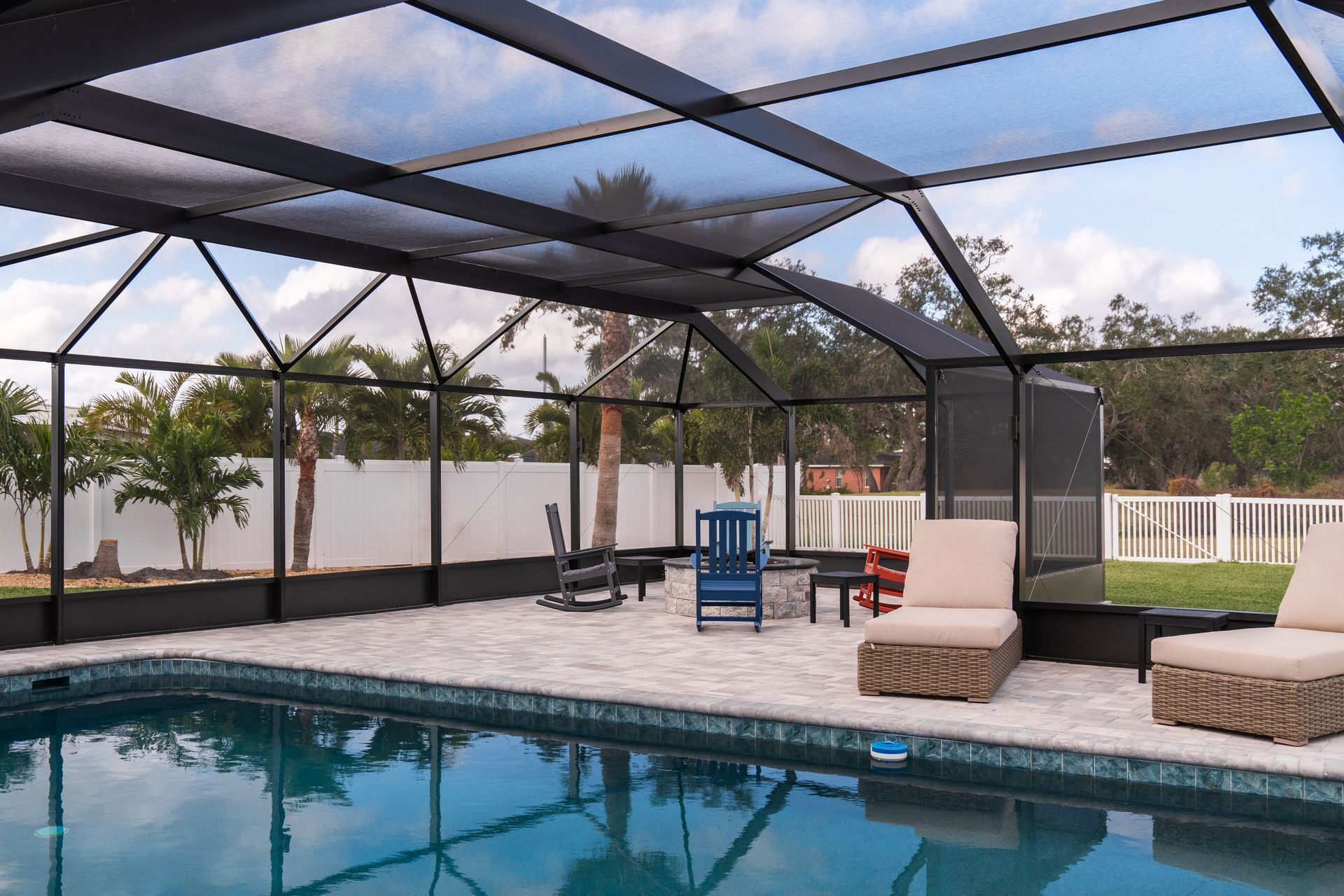 A swimming pool with a screened in area and chairs around it