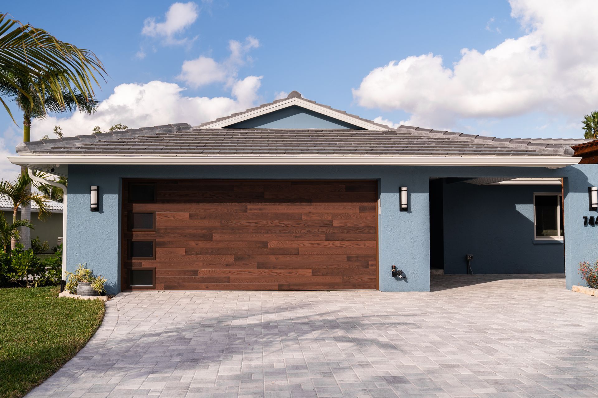 A blue house with a wooden garage door and a driveway.