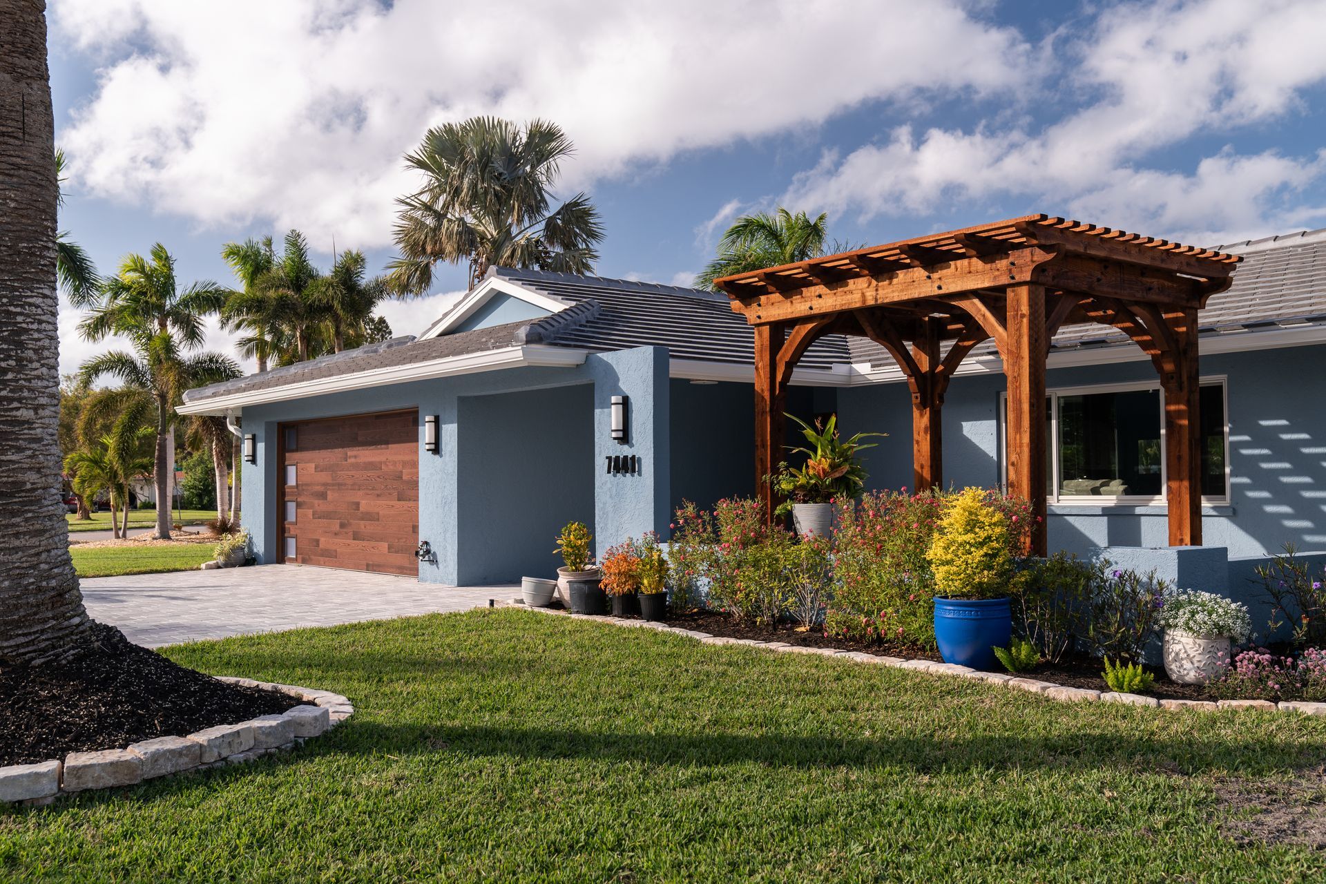 A blue house with a wooden pergola in front of it.