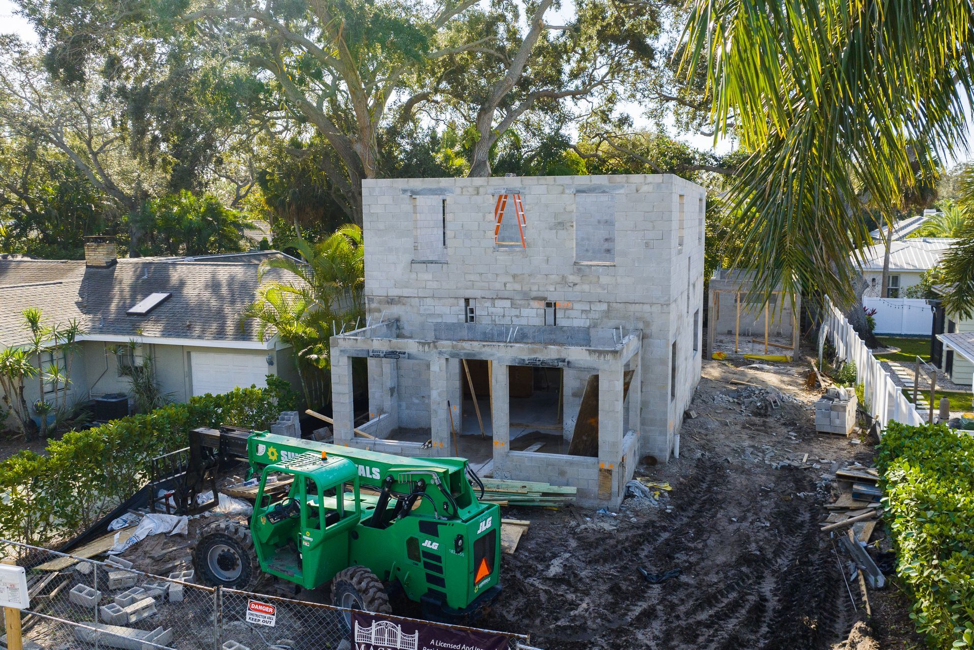 An aerial view of a house under construction with a green forklift in front of it.