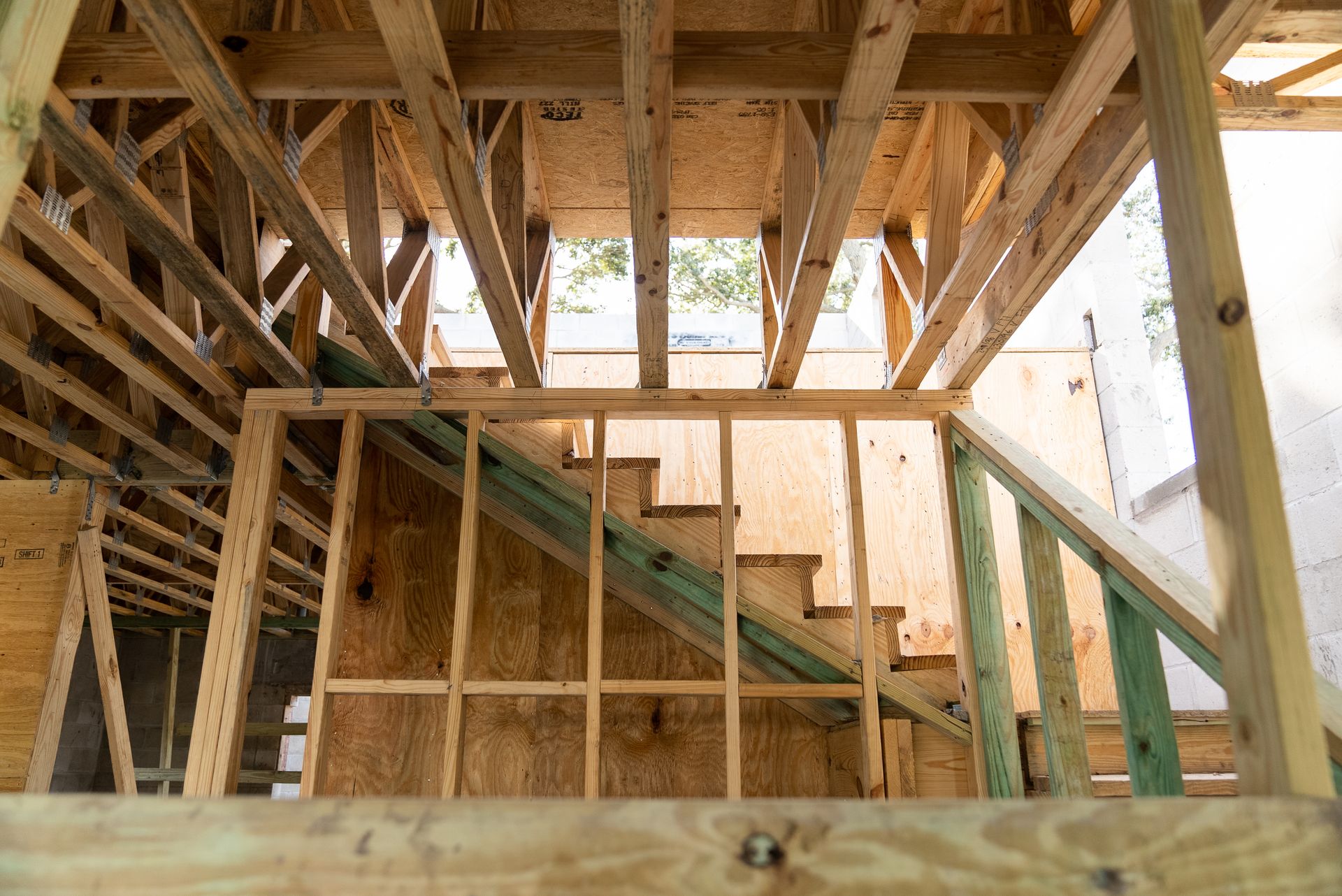 A wooden staircase is being built in a house under construction.