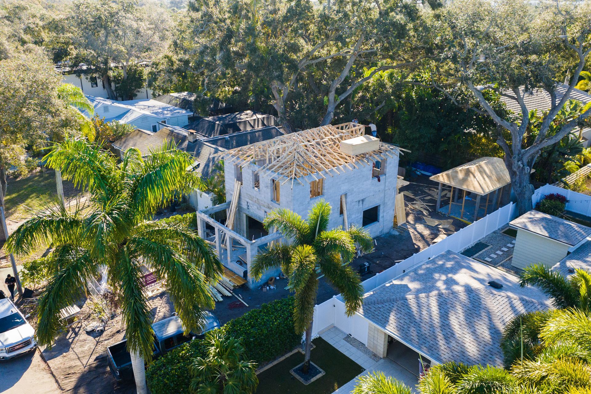 An aerial view of a house under construction in a residential area surrounded by trees.