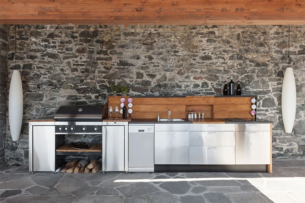 A kitchen with a stone wall and stainless steel cabinets