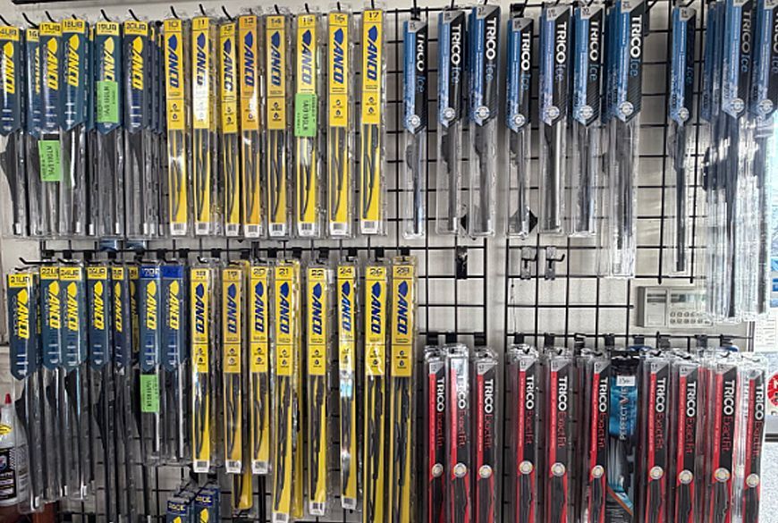 Windshield wiper blades displayed on a retail store rack, various lengths and colors.