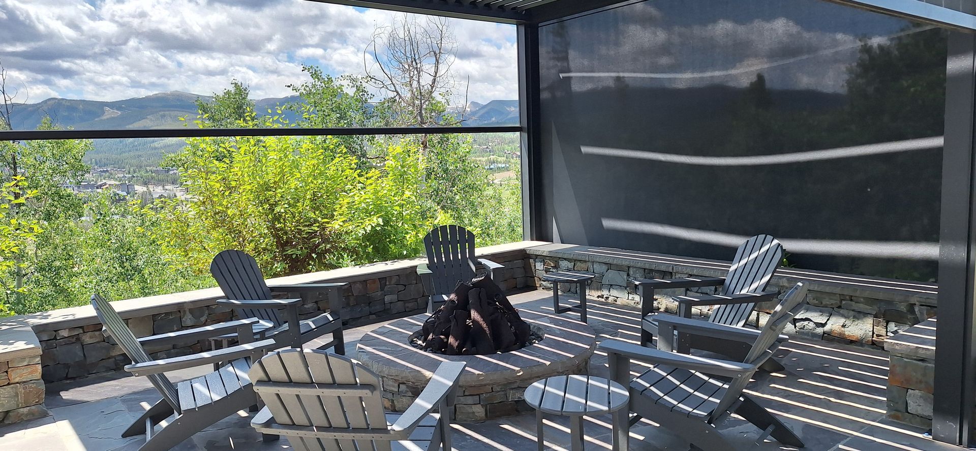 Patio with white lounge chairs, grill, and mountain lake view under a covered deck