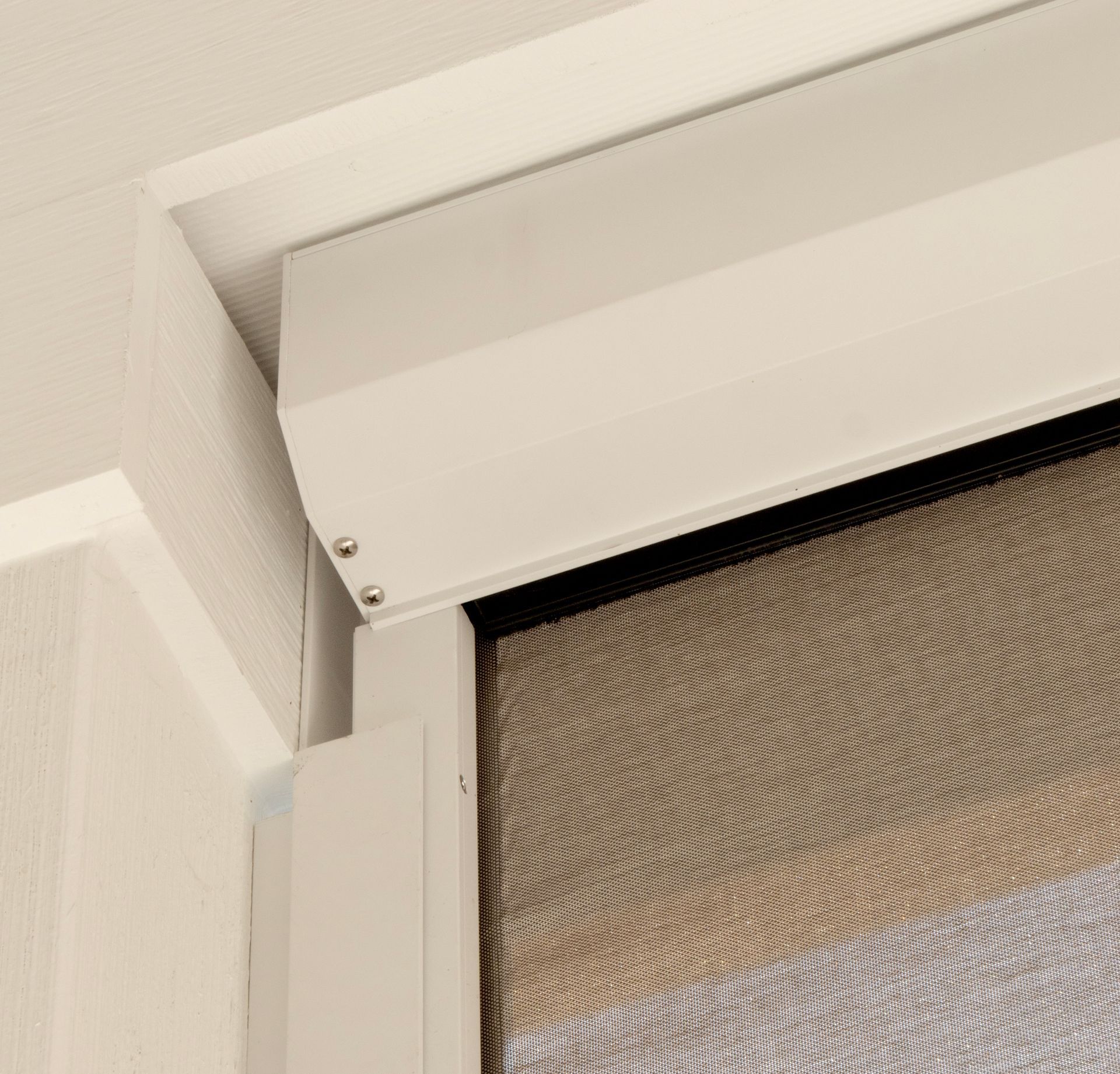 White window blind with mesh screen in a corner, viewed close up