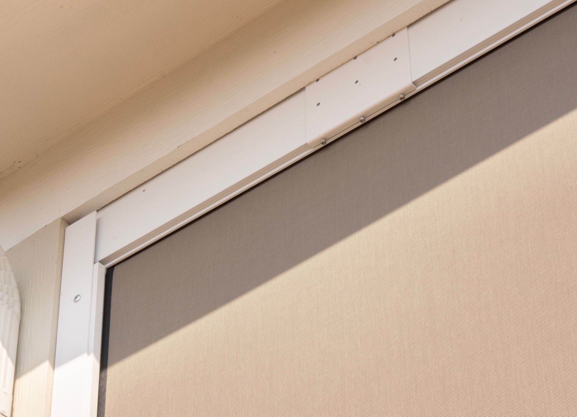 Close-up of a beige roller blind inside a window frame near the ceiling