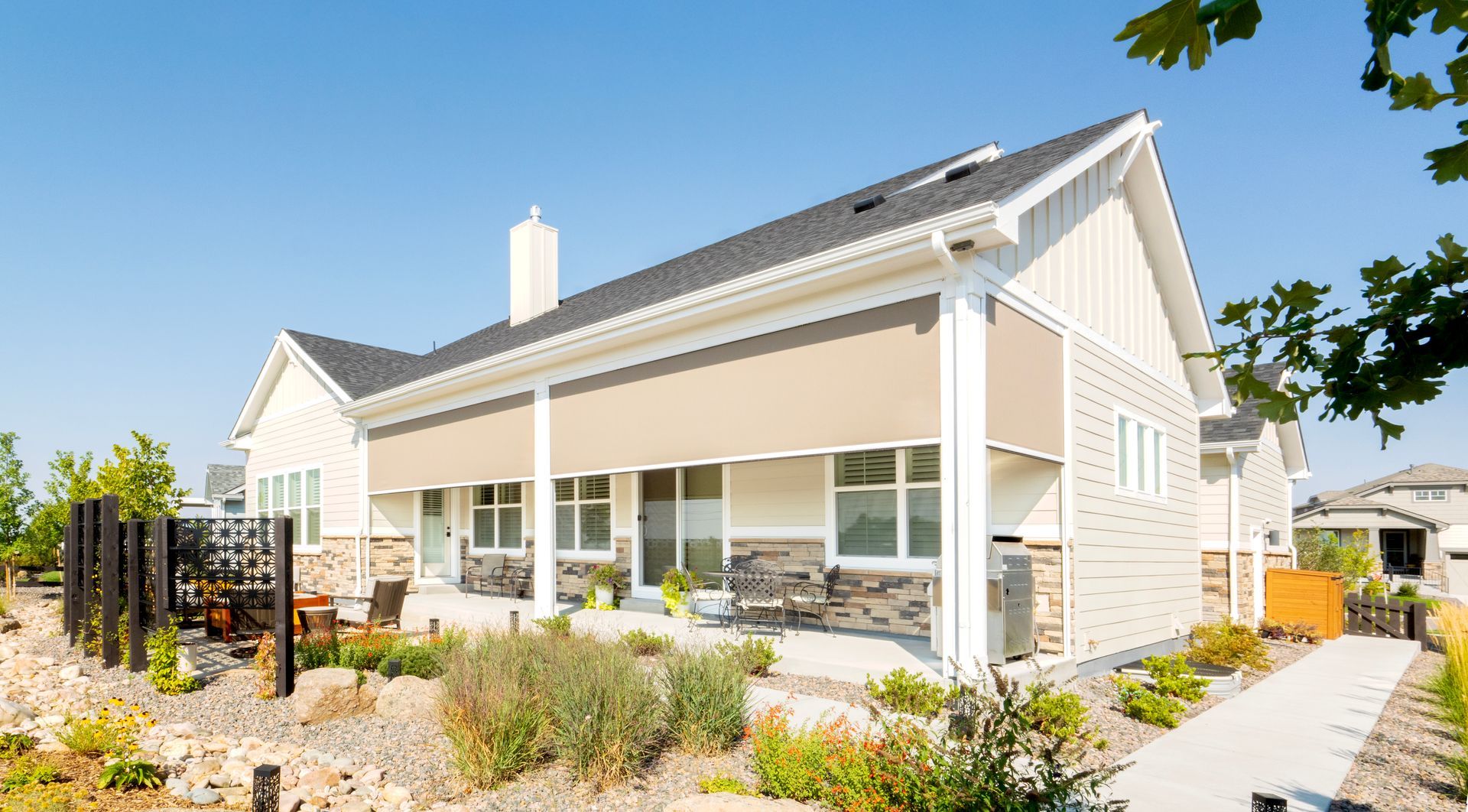Modern white beach house with large windows, surrounded by desert landscaping under a clear blue sky