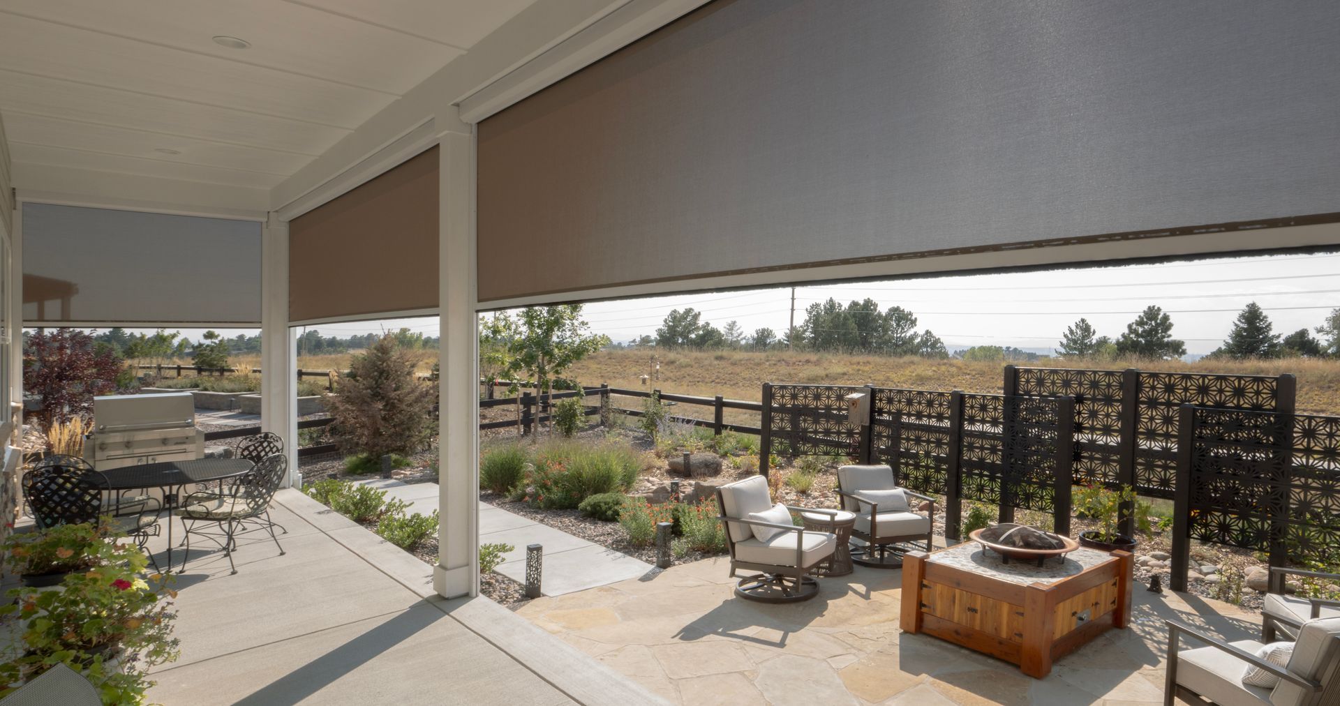 Covered patio with outdoor seating, potted plants, and a view of a landscaped yard