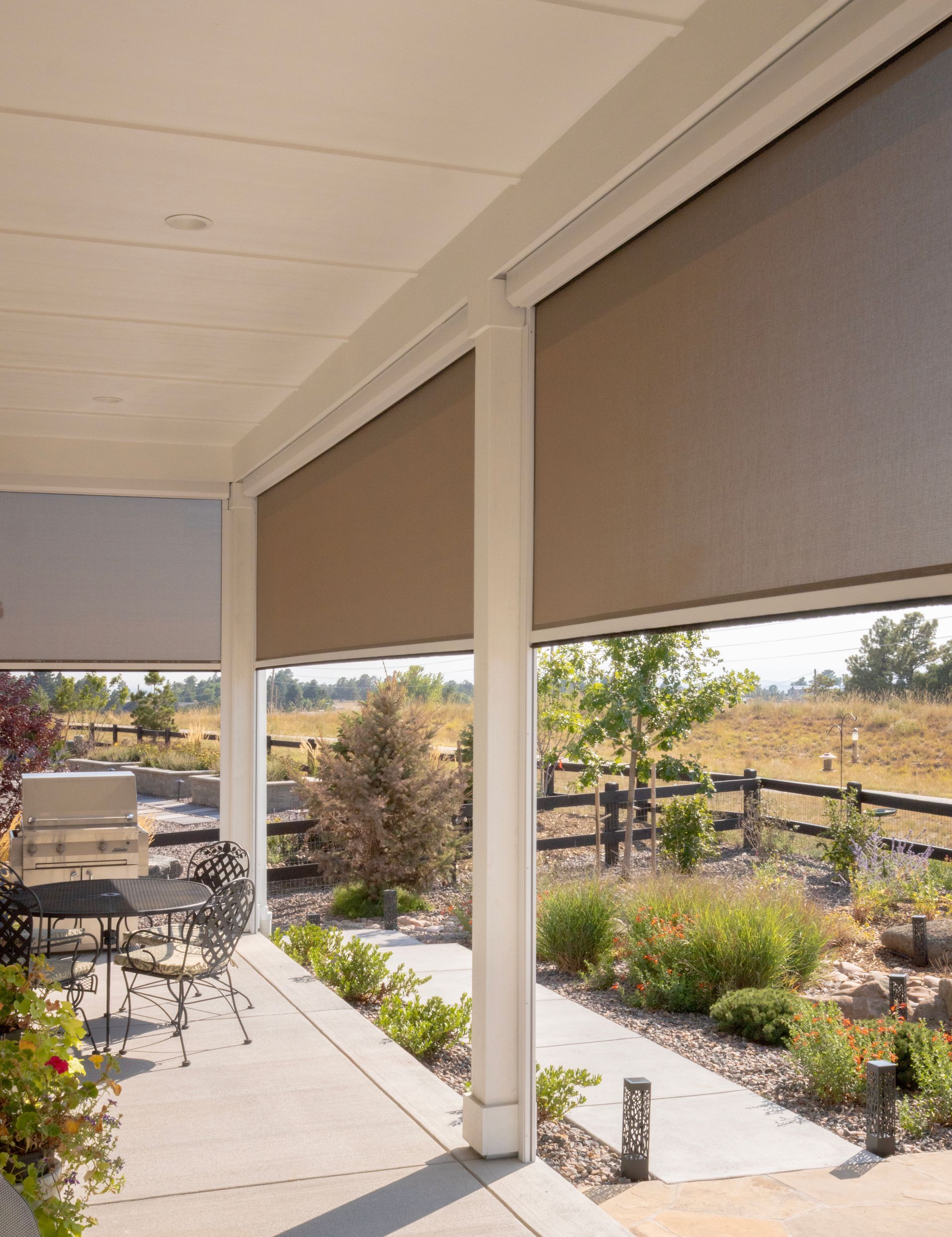 Covered patio overlooking a landscaped garden and fenced field on a sunny day