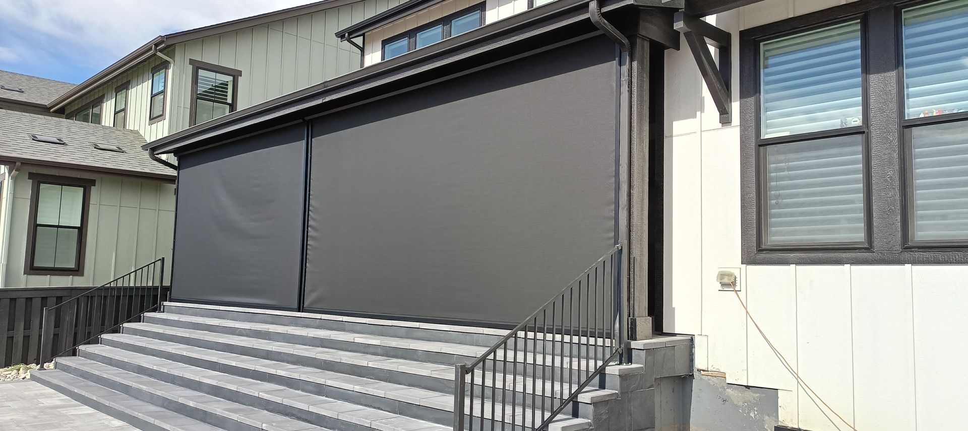 House exterior with large gray roll-down shutter over a porch and striped metal awning