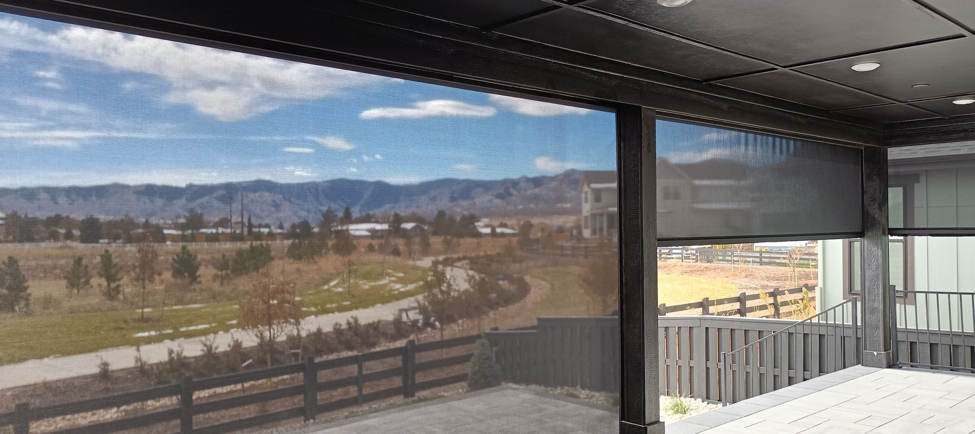 Covered patio overlooking a sunny landscape with mountains, trees, and a road in the distance