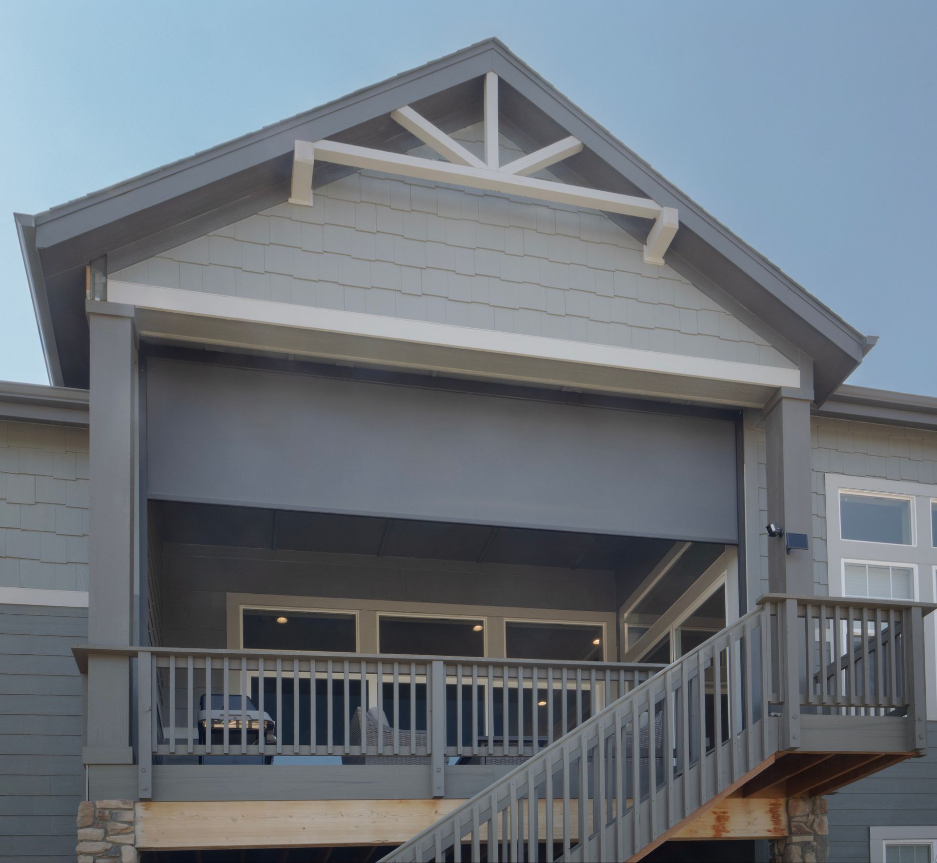 Gray house exterior with covered balcony, white trim, and stairs leading up to the porch