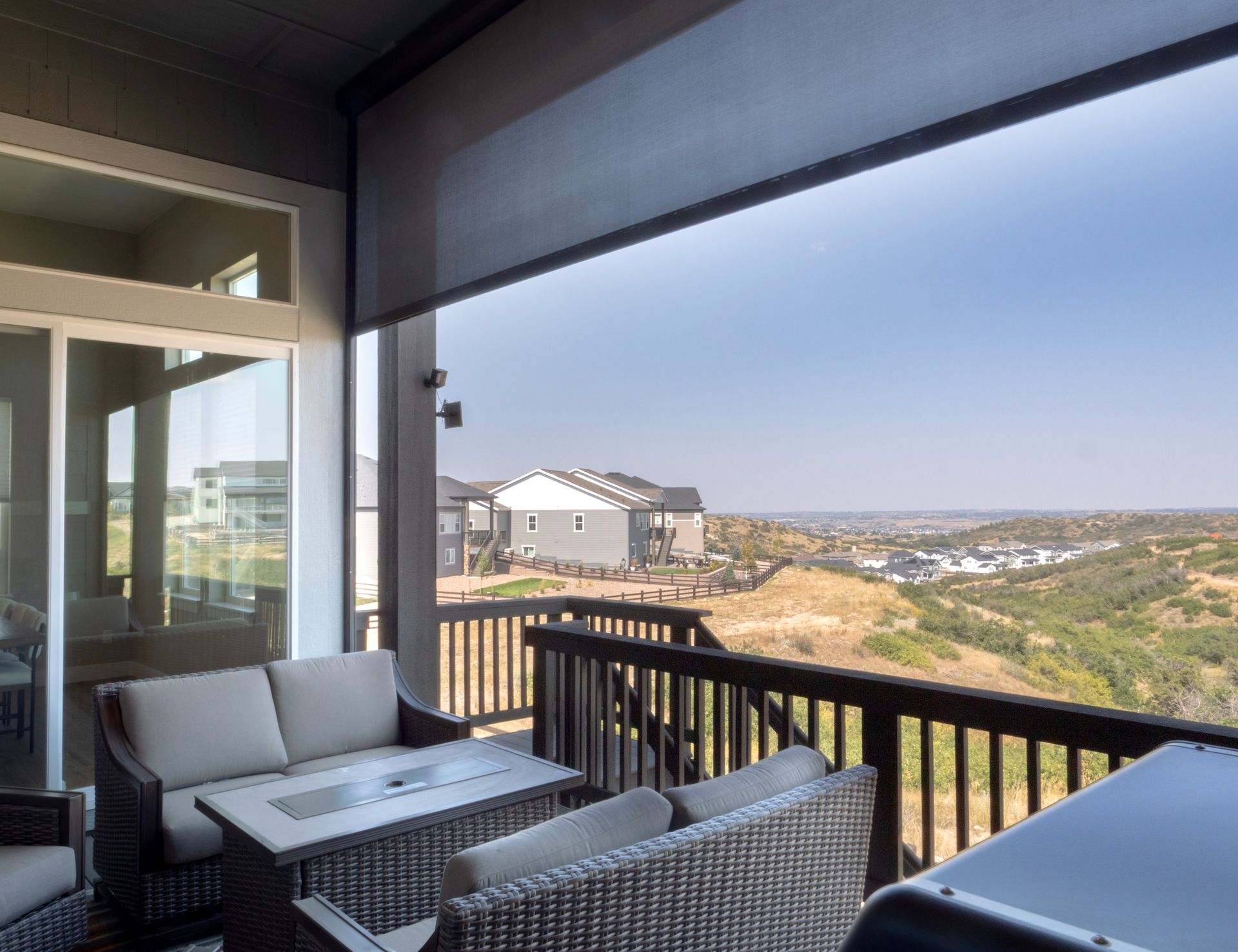 Covered patio with outdoor seating overlooking a hillside neighborhood and distant landscape